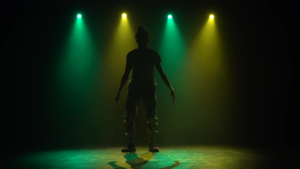 Silhouette Man Enjoying Hip Hop Moves in Dark Studio with Smoke. Green and Yellow Lighting. Slow alt