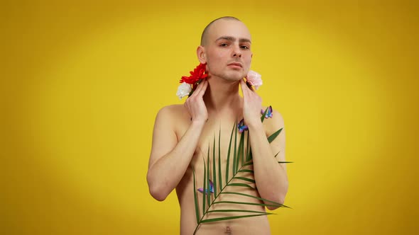 Expressive Male Queer Covered with Flowers and Butterflies Posing at Yellow Background alt