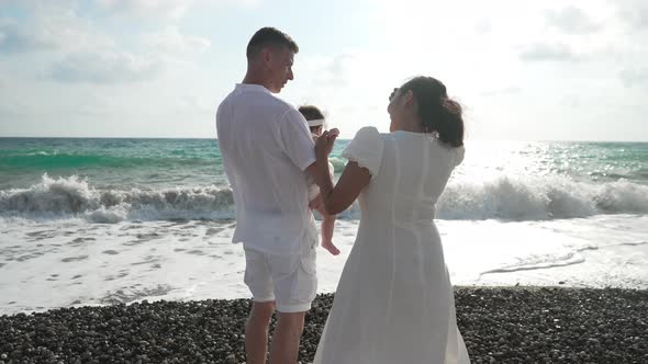 Back View of Happy Young Couple of Parents Holding Baby Daughter Admiring Sunset on Picturesque alt