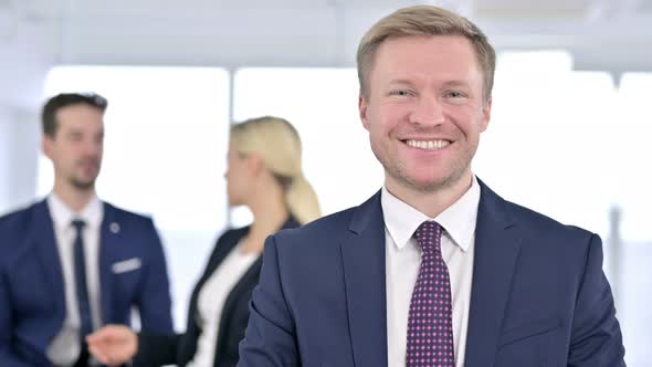 Portrait of Cheerful Businessman Smiling at the Camera in Office alt