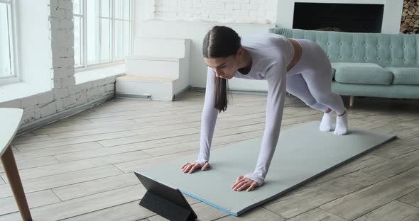 Athletic Young Woman Watching Video Tutorial on Tablet Doing Exercises alt