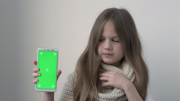 Little Girl Coughing Sneezes and Shows Phone with Green Screen Mock Up alt