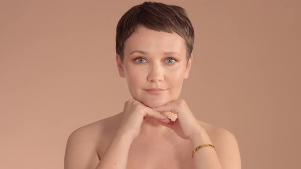 Caucasian Woman with Short Haircut and Natural Beige Makeup in Studio on Beige Background