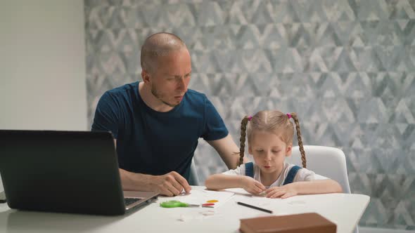 Father Helps Daughter Glue Colorful Sticker on Paper alt