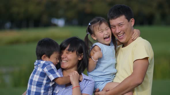 Excited Asian Family of Four Laughing in Park alt