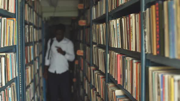 Blonde Teacher Searching Book in the Library in School alt