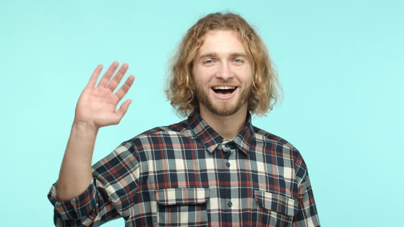 Slow Motion of Friendly Blonde Hipster Guy Saying Hello Waving Hand and Saying Hi to Camera Smiling