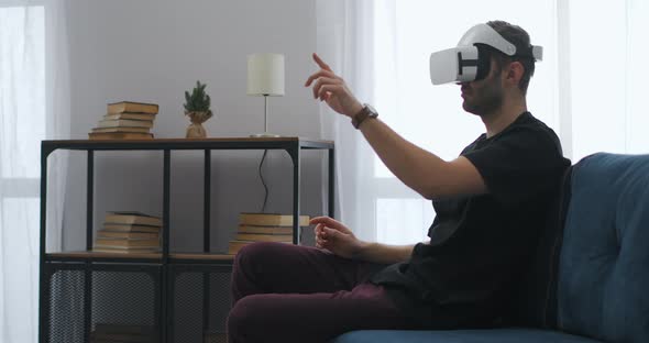 Virtual Reality Technology for Home Use Man is Wearing Headmounted Display and Controlling By Hands alt