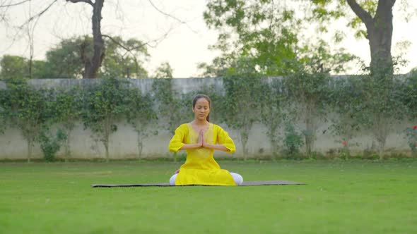 Namaste Yoga pose or Namaskarasana is being done by an Indian woman in a park alt