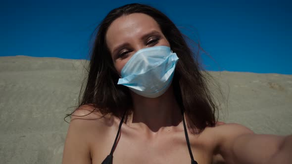 A Girl in a Medical Mask During a Coronavirus on the Beach. Pandemic 2020.