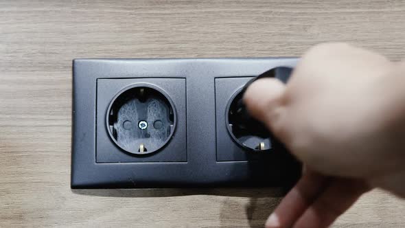 Hand Inserts the Plug Into Electric Socket