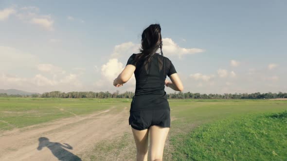 follow shot Asian woman running on a rural road in the mountain view beautiful sunset. alt