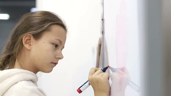 Little Schoolgirl Girl Writes a Marker on the Blackboard at School alt