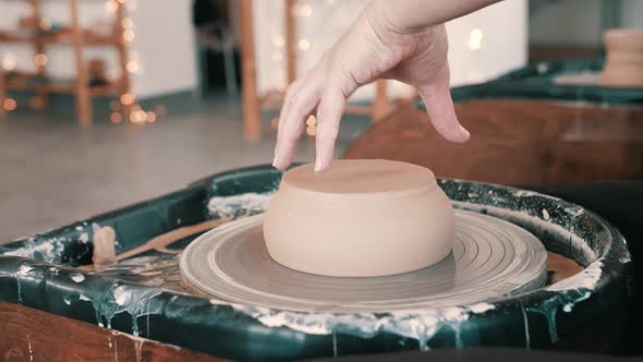 Potter aligns a clay bowl on a potter's wheel