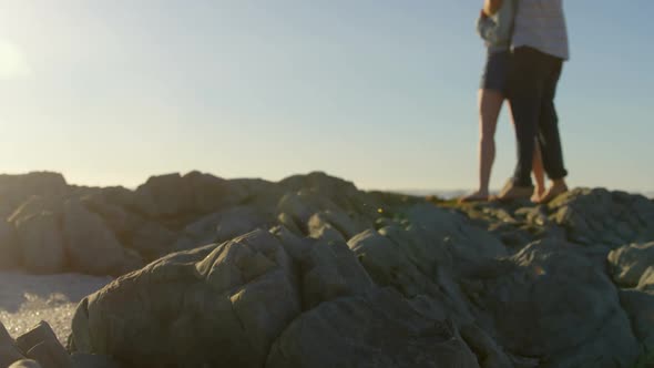 Romantic young couple embracing on rock at beach 4k alt