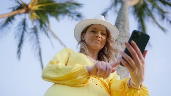 Cheerful Woman on Island Beach Take Selfie Portrait with Green Palms Background alt