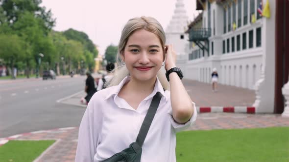 Portrait young Asian woman smiling looking at the camera standing on the street.