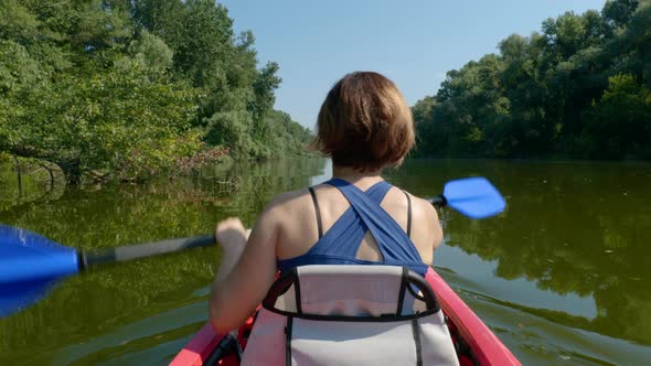 Woman Swims on a Kayak on a Calm River alt