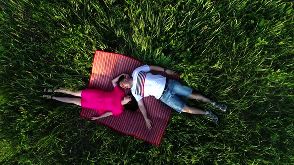 Top View of a Couple in Love Lying on the Grass and Looking at Each Other. View From a Drone.