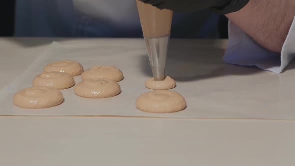 A Male Confectioner Squeezes Pasta Dough Out of a Pastry Bag Onto a Silicone Mat with Special