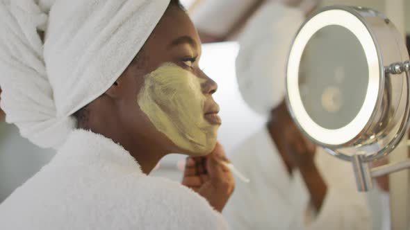 Profile of african american attractive woman applying face mask in bathroom alt
