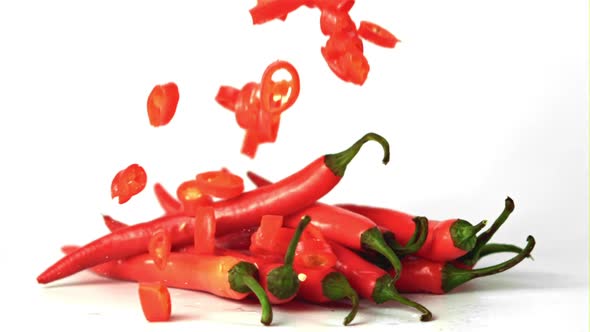 Super Slow Motion Pieces of Chili Pepper Fall on a Bunch of Pepper Pods alt
