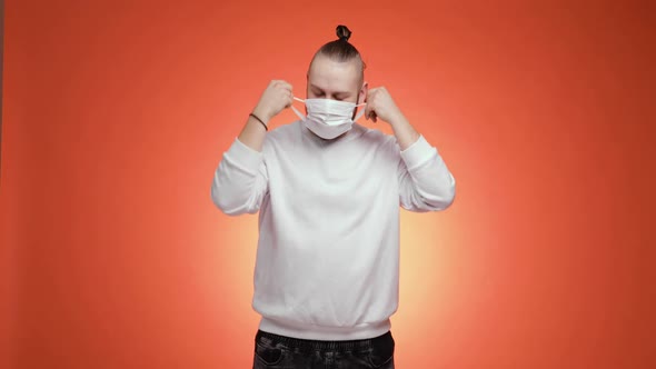 Bearded Man Takes Off Medical Mask and Makes Deep Breath on Red Background alt