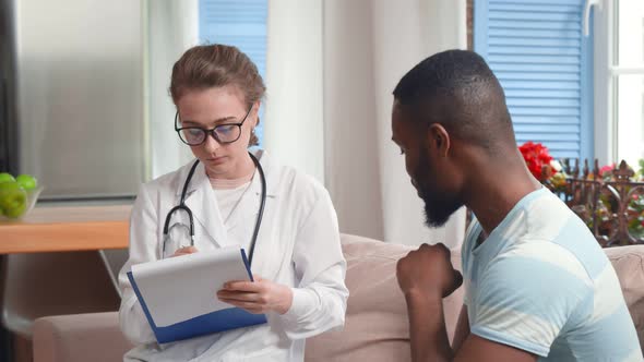 Female Doctor Consulting Patient During Home Medical Care Visit alt