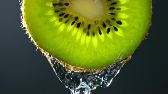 Super Slow Motion Macro Shot of Flowing Water From Kiwi Slice on Black Background at 1000Fps alt