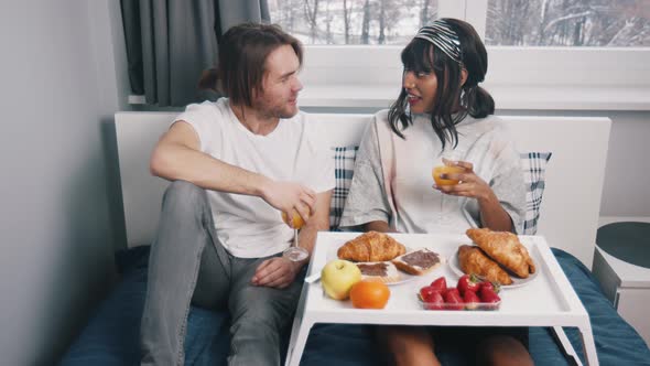 Young Multiracial Newlywed Couple Having Breakfast in the Bed on the Honeymoon alt