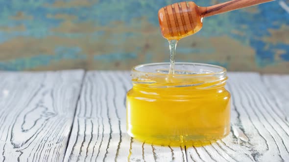 Honey in Glass Jar with Honey Dipper Over Rustic Wooden Background alt