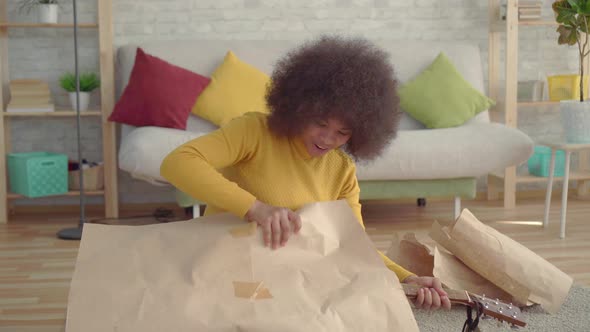 Portrait African Woman with an Afro Hairstyle Unpacks a New Guitar alt