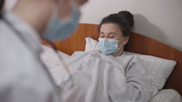 Portrait of Young Woman Lying in Bed in Hospital Ward Talking to Doctor Complaining Symptoms alt