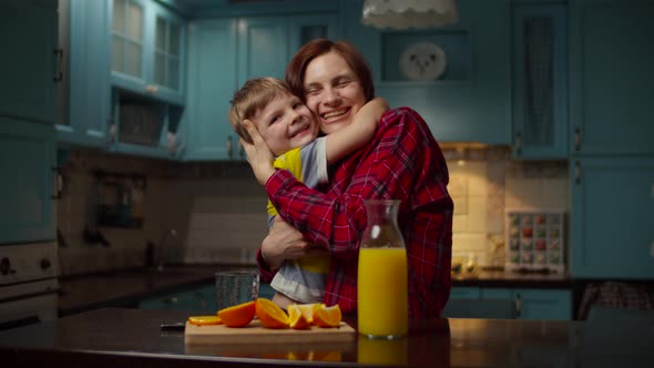 Woman Pouring Orange Juice Into Glass for Boy. Young 30s Mother and Son Enjoying Family Time on alt