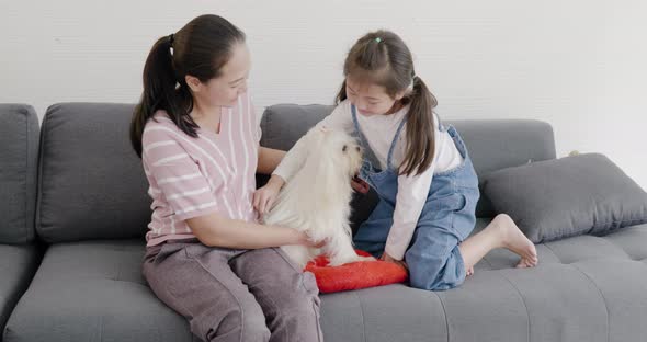 Mom and daughter playing with white dog on sofa 3