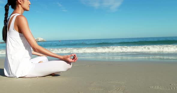 Woman performing yoga at beach alt