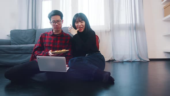 Happy Young Couple Watching Movies on the Laptop or Browsing Social Media with Snack alt