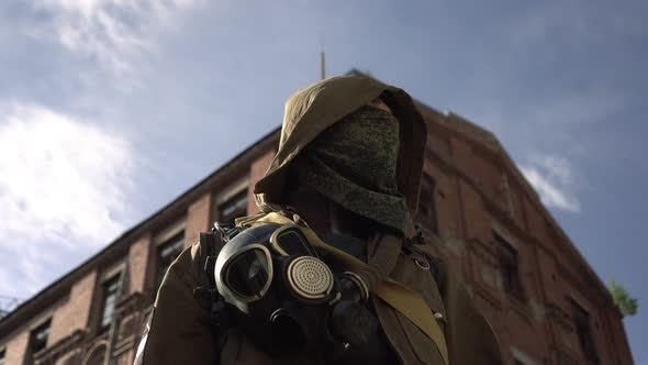 A Man Stalker or Soldier in Gas Mask Against Background of a Destroyed Building alt