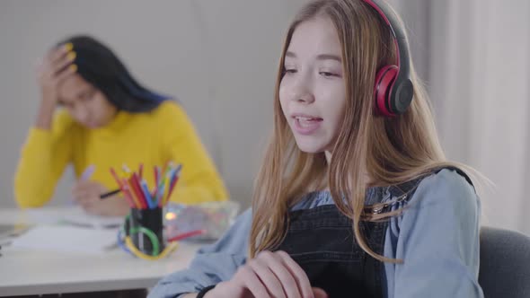 Portrait of Beautiful Caucasian Girl in Headphones Singing and Dancing While African American Teen alt