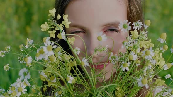 Closeup of a Girl's Face Looking Through a Bouquet of Wildflowers