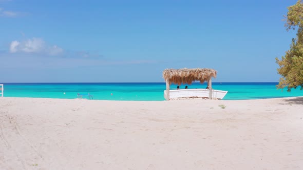 Tourists sitting under seafront gazebo on beach at Eco del Mar, Pedernales. First-person view alt