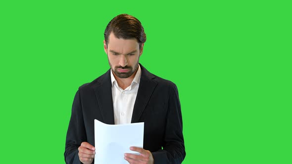 Young Business Man Looking Through the Documents on a Green Screen Chroma Key alt