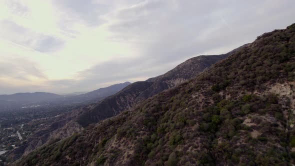 A drone shot over a large mountain range at golden hour. Reveals another mountain. alt