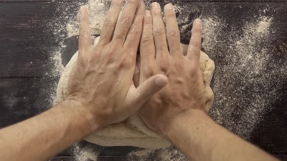 Baker's hands kneading bread dough from a top view or pov.
