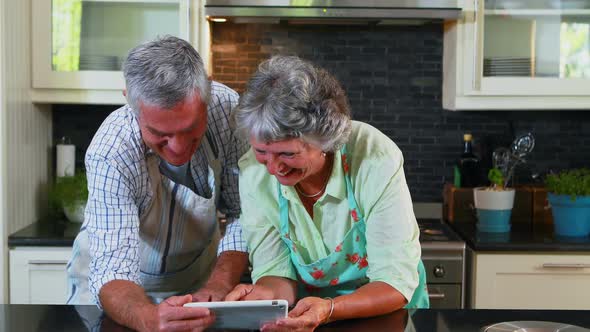 Senior couple using digital tablet in kitchen 4k alt