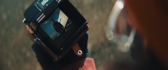 Close up an checking video on preview screen of his vintage camera alt