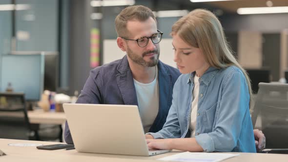 Male Colleague Harassing Female Colleague While Working on Laptop in Office alt