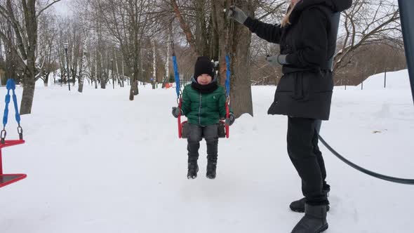 Little Asian Boy Swinging on a Swing in Winter Park alt