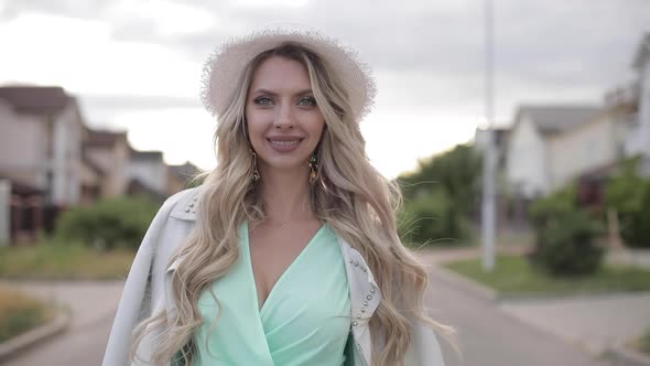 Portrait of Beautiful Woman in Long Mint Dress, White Hat and White Jacket Smiles