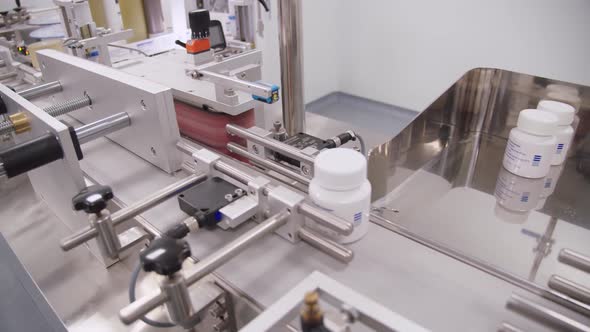 Packaged Plastic Containers with Drugs Move on Conveyor Belt in the Workshop of Medicine Production